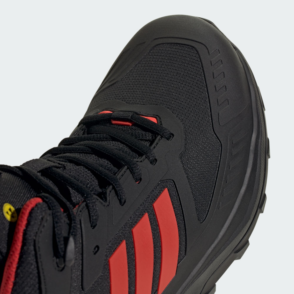 Nahaufnahme eines schwarzen Adidas Outdoor-Schuhs mit roten Akzentstreifen, robuster Sohle und schwarzen Schnürsenkeln