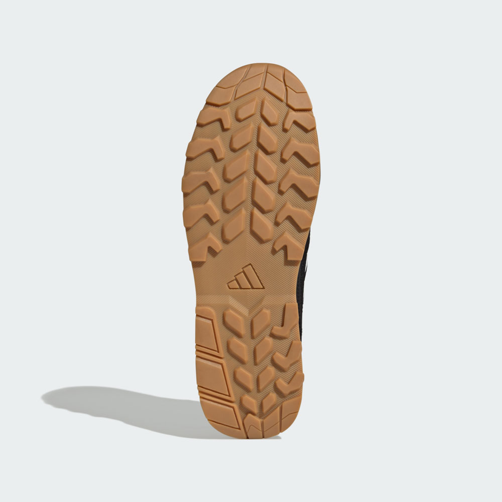Unteransicht eines adidas Schuhs mit grobem Gummiprofil in Braun und schwarzem Obermaterial, ideal für Outdoor und Trail