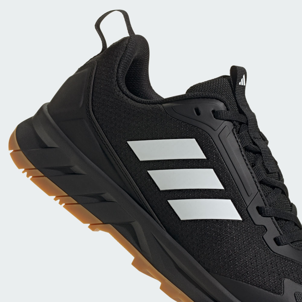 Nahaufnahme eines schwarzen adidas Sneakers mit den drei weißen Markenstreifen und robuster Gummisohle in Braun-Schwarz