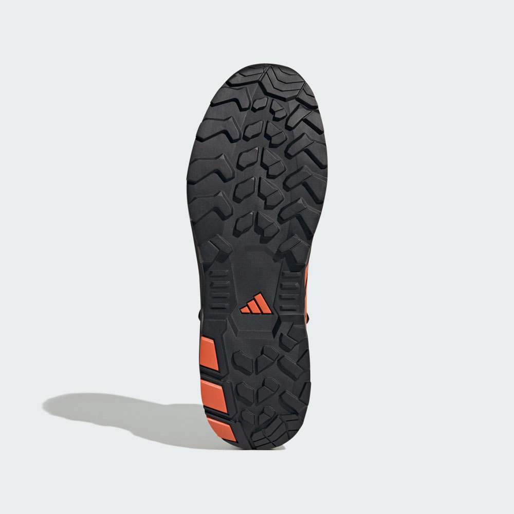 Unterseite eines adidas Outdoor-Schuhs mit grobem Stollenprofil in Schwarz und Orange für optimalen Grip