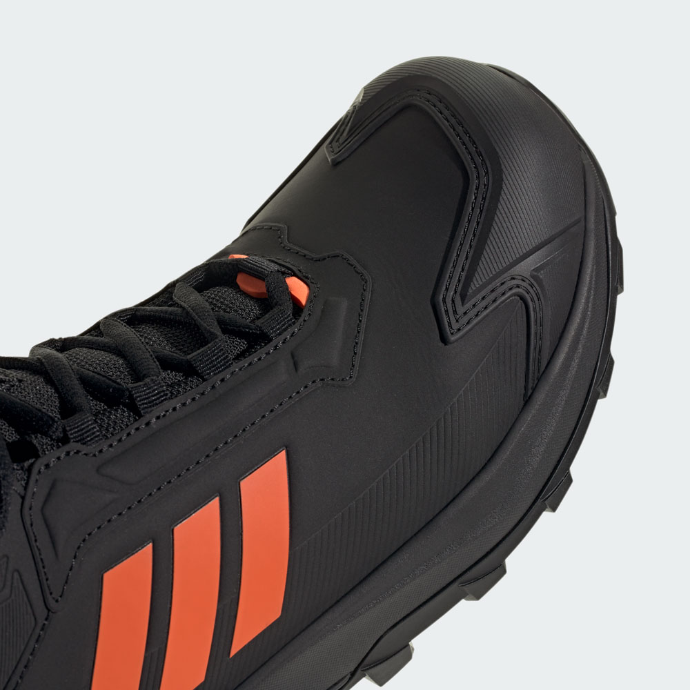 Nahaufnahme eines schwarzen adidas Trailrunning-Schuhs mit orangefarbenen Seitenstreifen, robuster Profilsohle und verstärkter Zehenkappe