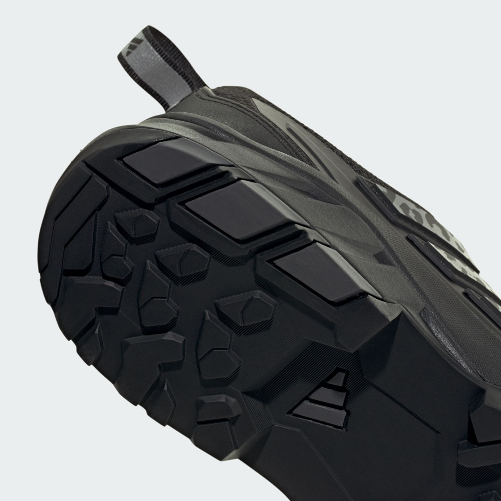 Nahaufnahme der robusten Profilsohle eines schwarzen adidas Schuhs mit Trittschlaufe für optimalen Grip im Gelände