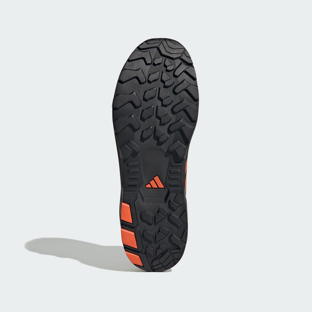 Unteransicht der robusten Gummisohle eines adidas Outdoor-Schuhs mit tiefem Profil und orangefarbenen Akzenten für optimalen Grip