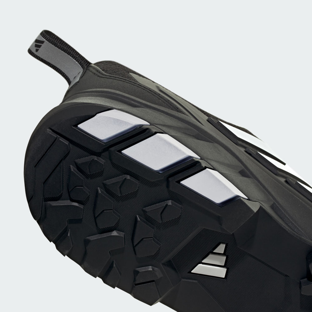 Nahaufnahme der schwarzen Gummisohle eines adidas Outdoor-Schuhs mit tiefem Stollenprofil für optimalen Grip auf unebenem Gelände
